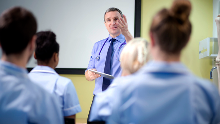 Health care professor in front of classroom 710x400 Professor in shirt and tie in front of classroom lecturing