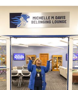 Micki Davis standing below the sign identifying the student lounge named in her honor