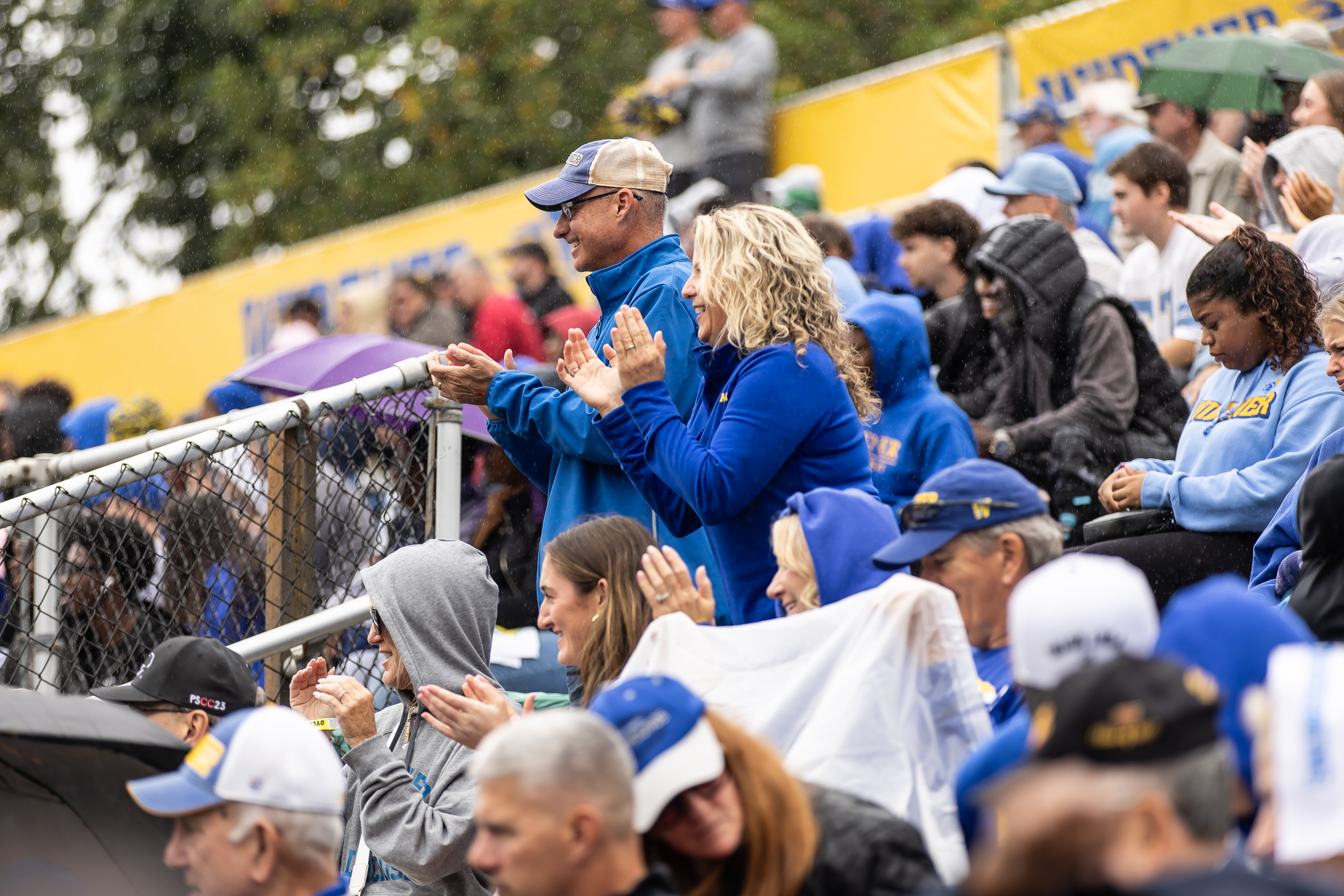 Fans stand in the stadium to cheer on the game.