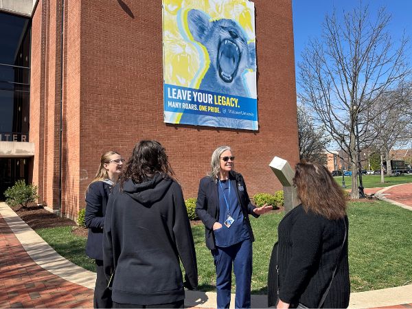 President Robertson stands in front of Kapelski giving a tour to a prospective student and her mother.