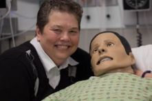 Nursing PhD student Deb Halliday posing with a medical manikin