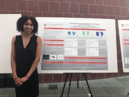 Autumn Campbell poses in front of a research poster presentation.