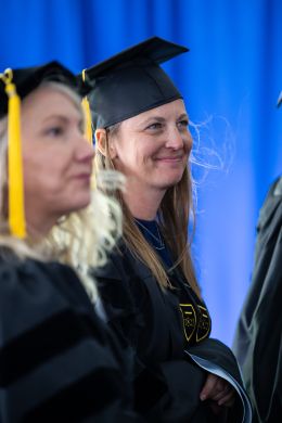 Graduate students seated at commencement, smiling