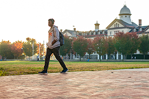 Student walking across Widener's campus in the fall