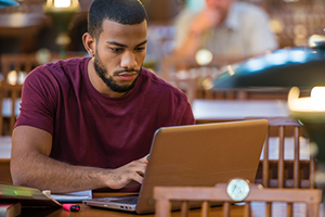 Student studying on laptop in historic-looking library
