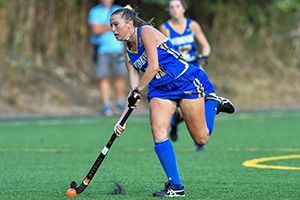 Widener field hockey player dribbling on turf field