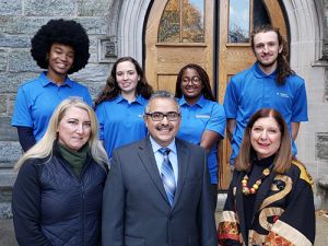 Seven people, including four Widener students in matching blue shirts, pose for a photo