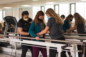 Occupational and physical therapy students assist a client during a walking exercise in the community clinic.