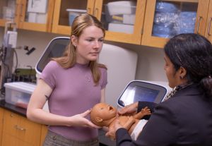 A graduate biomedical engineering student holds a baby manikin during a lesson.
