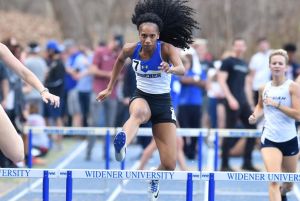 Aishah Dukes leaps over a hurdle during a track and field meet.