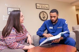 Isaiah Washington sits with a nursing professor going over a textbook.