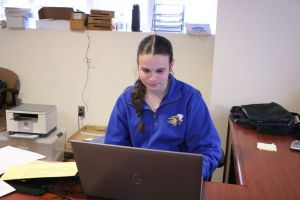 Angelina Breen working at a laptop wearing a Widener jacket