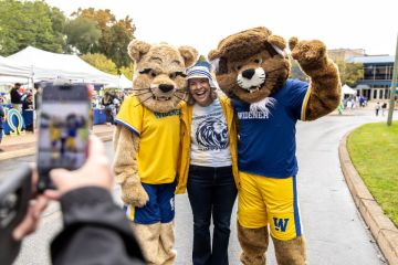 Stacey Robertson smile with the mascots at homecoming.