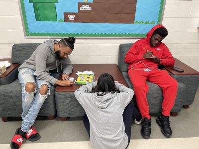 Three students in the 1821 Experience LLC sit in a lounge working on diversity puzzle activity