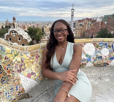 Ja'Lisa Williams seated in front of a wall of colorful mosaic tiles; behind her is the skyline of Barcelona