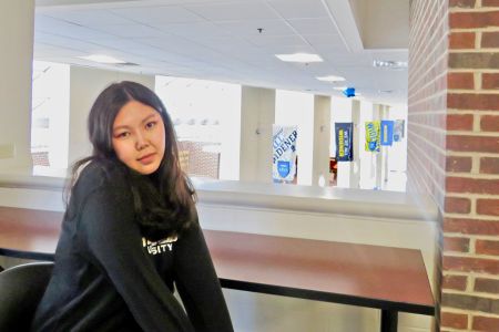 International Student Tsatsral Sugar sits on the second floor of the University Center; behind her are Widener flags hanging from the ceiling
