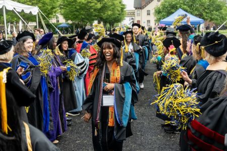 Commencement 2025 grad processional 960 x640 A female graduate student walks through the applause tunnel on her graduation day.