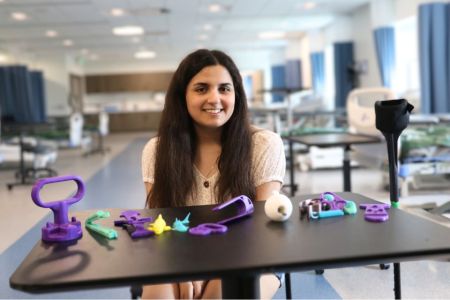 Lydia Aruffo Makers Lab 960 x 640 Lydia Aruffo ’25, a recent occupational therapy graduate, sits with a small selection of the 3D printed assistive devices she printed from open-sourced files and customized for clients as part of her capstone project.