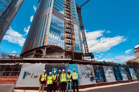 Students stand at a large skyscraper construction site.