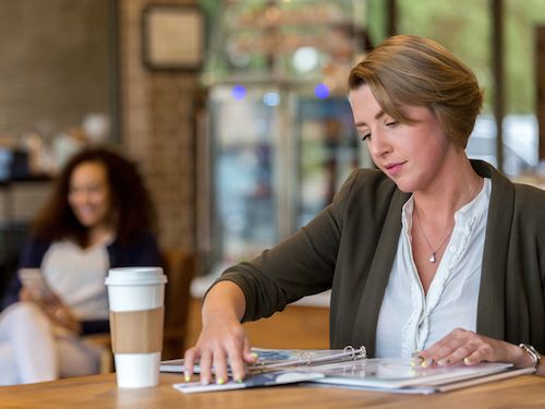 student studies in cafe with coffee and notebook