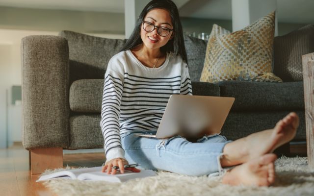 Student on laptop, sitting on ground, looking at paperwork